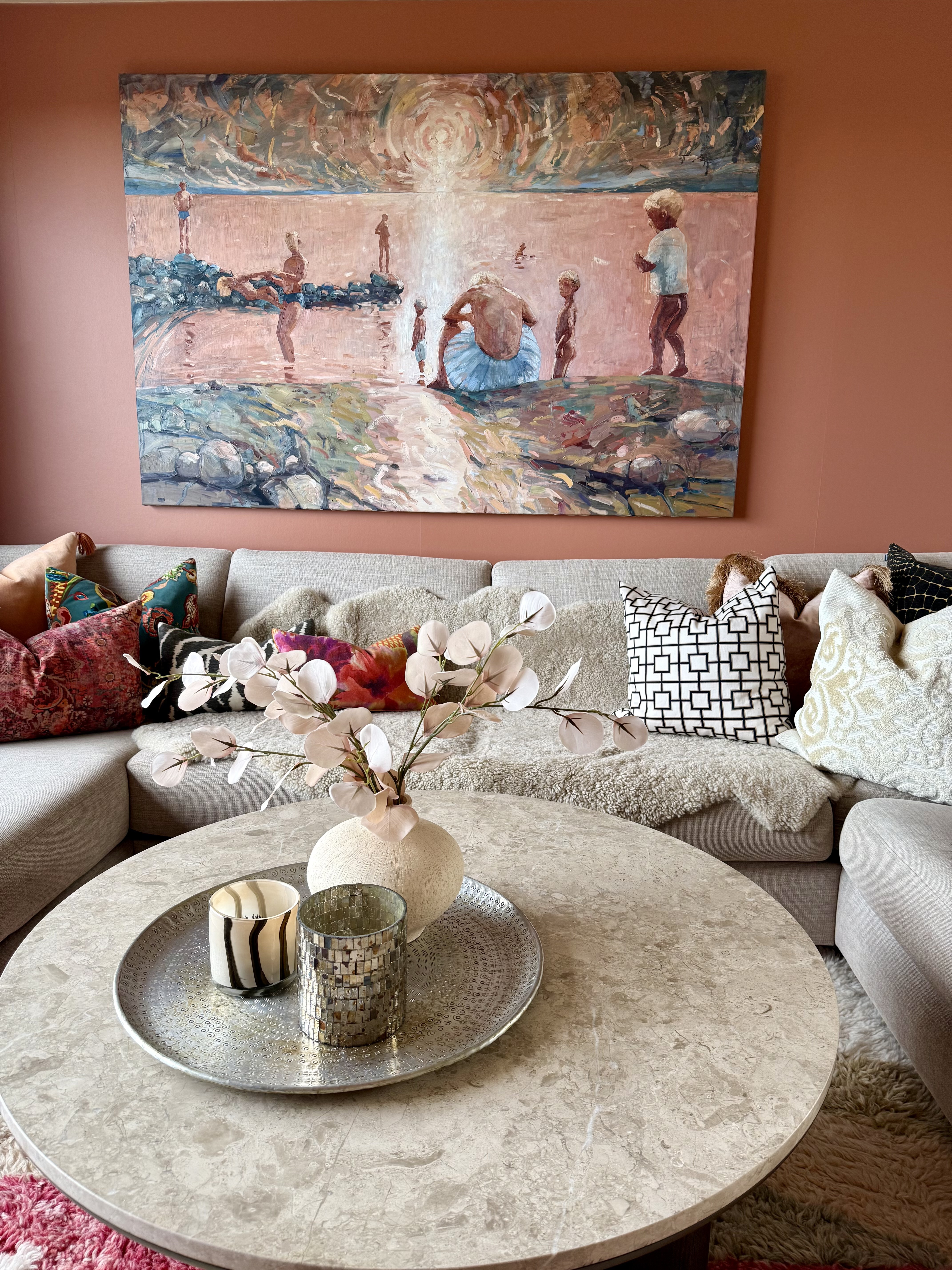 Stue med kunst over sofaen, personlige tekstiler og rundt salongbord
